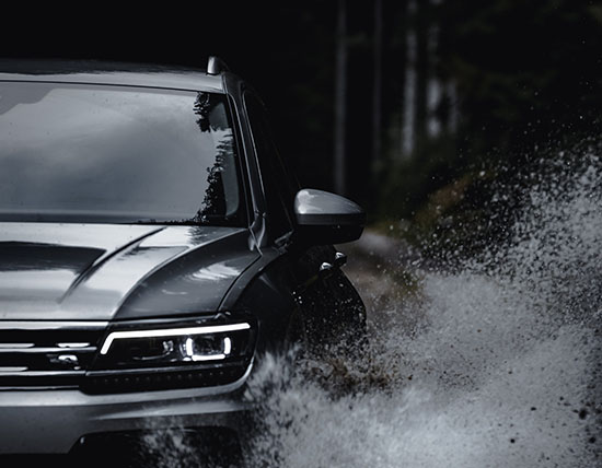 A modern SUV drives through a puddle