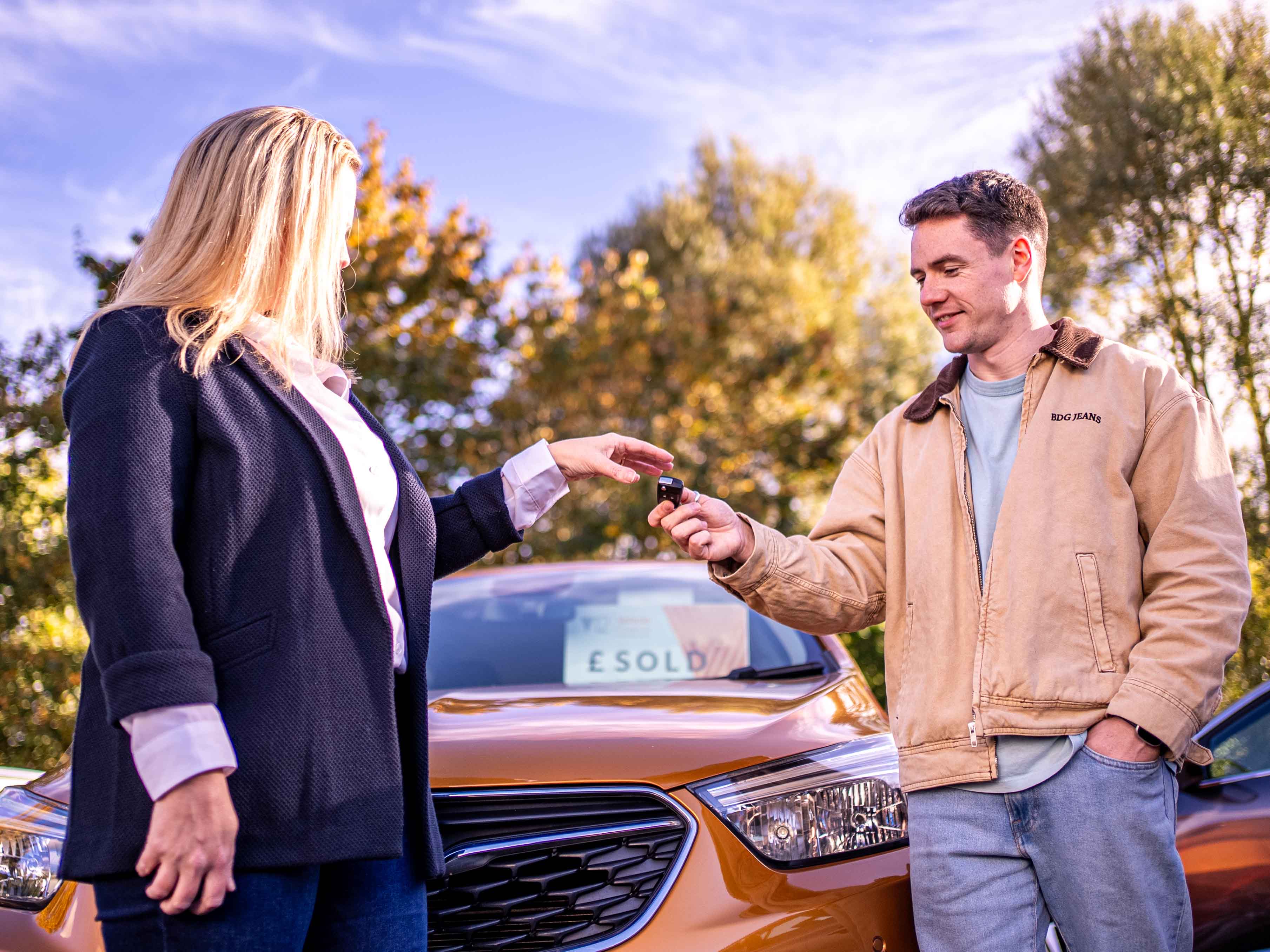 A dealer handing car keys to a happy customer