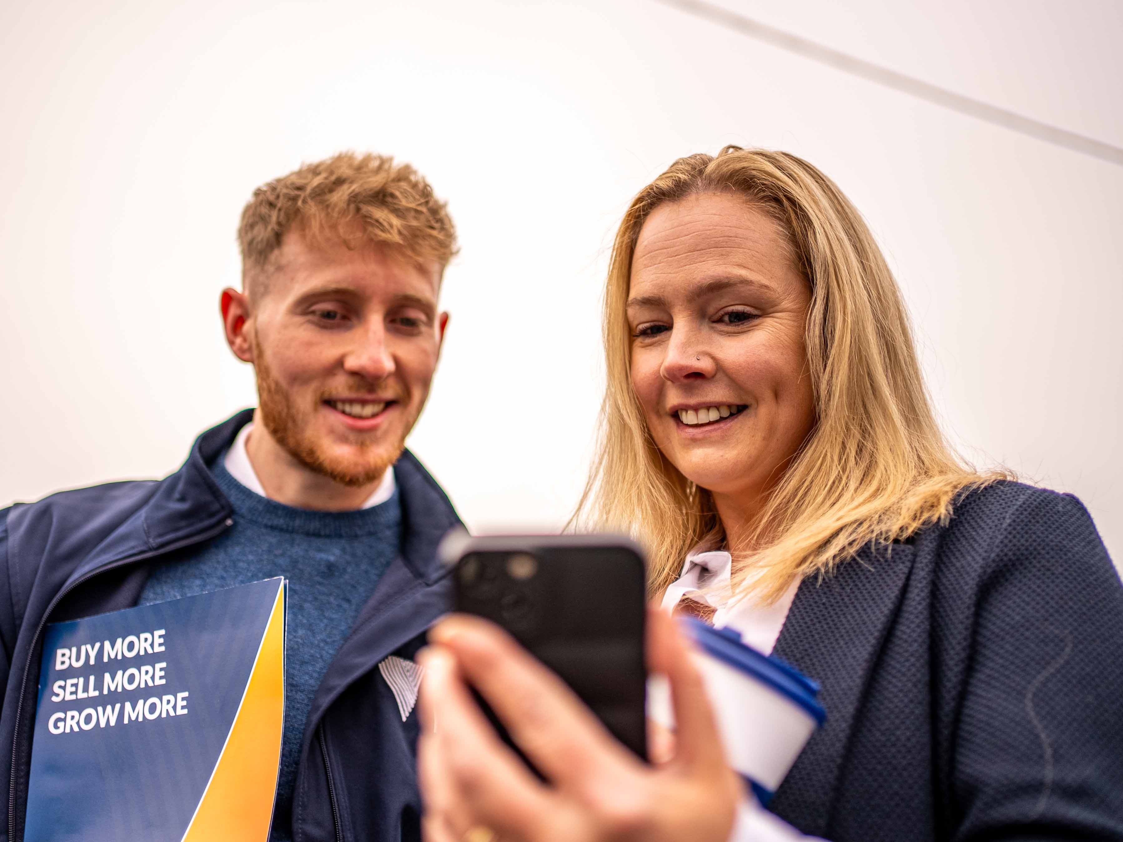 An account manager and a dealer looking at a phone smiling