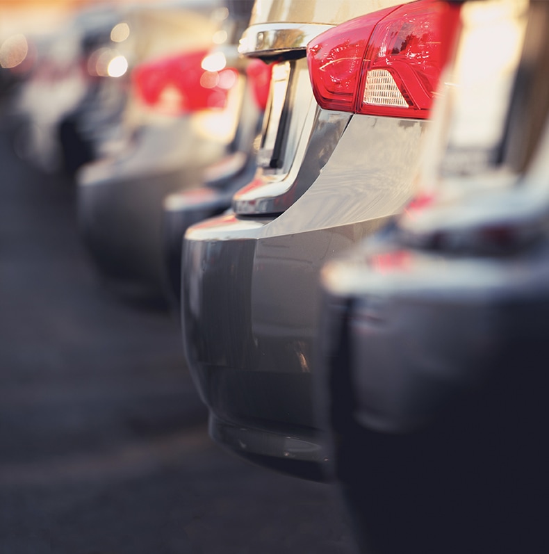 The rear bumper of a selections of grey parked cars